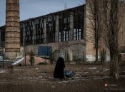 Бабуся везе воду на фоні обстріляного цеху