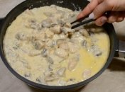 Курка з грибами та сиром у сметанному соусі на сковороді.