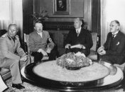 Беніто Муссоліні, Адольф Гітлер і Невілл Чемберлен у Мюнхені 1938 року ділять Європу.  Другий праворуч - Пауль Шмідт (перекладач)