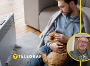 Мужчина с кошкой греется у обогревателя