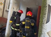 Спасатели заходят в задымленный подъезд.