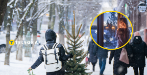 Сніжна святкова вулиця та дівчина, що дивиться у вікно