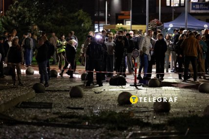 Люди чекають за огороджувальною стрічкою