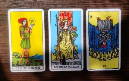 Слева направо — Паж пентаклей, Королева жезлов и перевернутая Девятка кубков