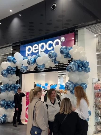 Вход в магазин Pepco с аркой из синих и белых шаров и посетителями