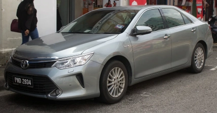 Сірий седан Toyota Camry припаркований біля магазину