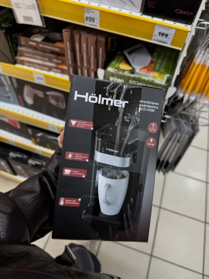 Покупатель держит коробку капельной кофеварки Hölmer HCD-015B в магазине