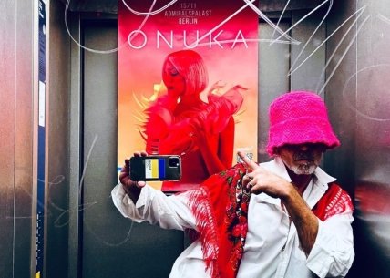 Франк перед афішею з анонсом концерту Onuka і у шапці, як у лідера гурту Kalush Orchestra