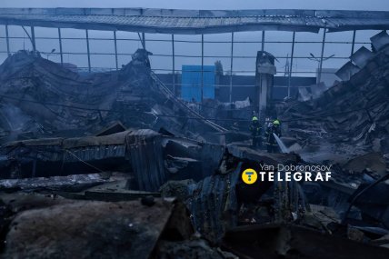 Два пожежники на згарищі, яке залишилось після горіння Епіцентру