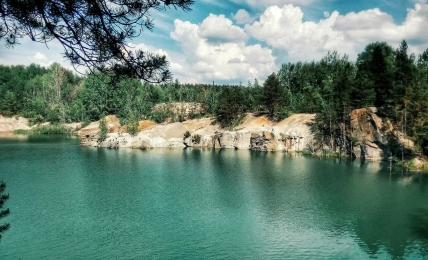 Бірюзова вода затопленого кар’єру, скелясті береги та ліс