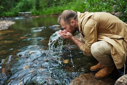 чоловік вмивається біля водоймища