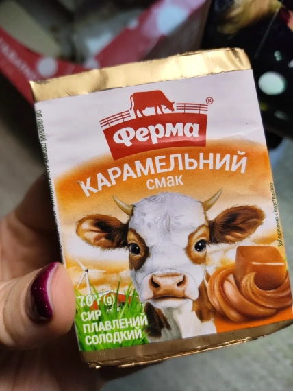Рука тримає упаковку плавленого сирка "Ферма" з карамельним смаком