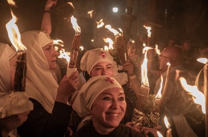 християнки тримають свічки з благодатним вогнем