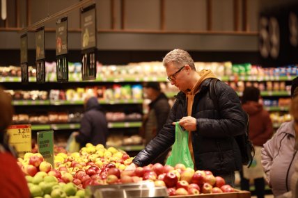 Человек выбирает яблоки в магазине Новус