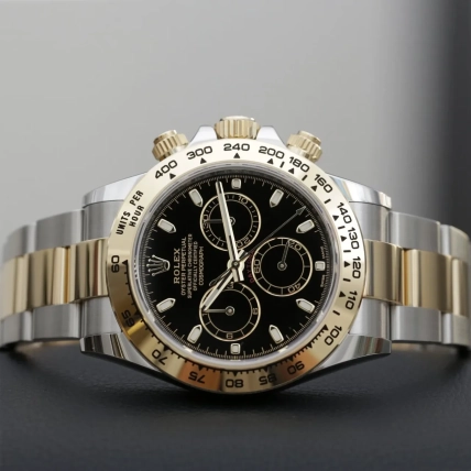 Крупний план годинника Rolex Daytona з чорним циферблатом, золотистим безелем і двоколірним браслетом
