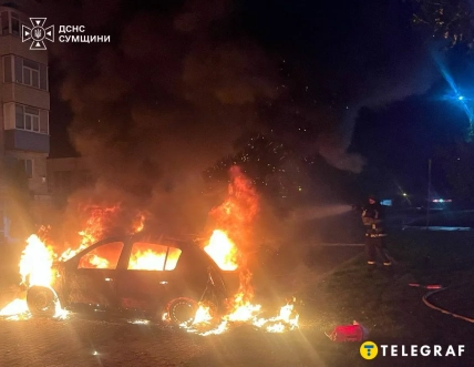 Легковий автомобіль охоплений вогнем, поруч стоїть рятувальник