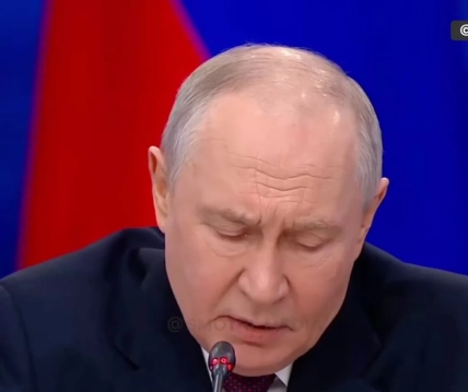 Крупний план Путіна в темному костюмі та бордовій краватці на червоно-синьому тлі
