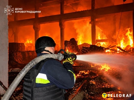 Рятувальник спрямовує струмінь води на вогонь у складському приміщенні
