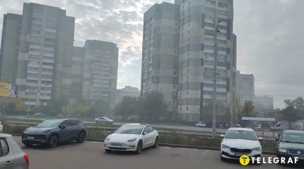 Многоэтажные жилые дома, припаркованные автомобили и остановка общественного транспорта