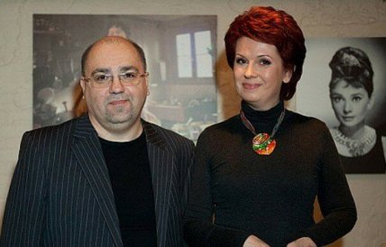 Мужчина в полосатом пиджаке и женщина с короткими рыжими волосами стоят рядом