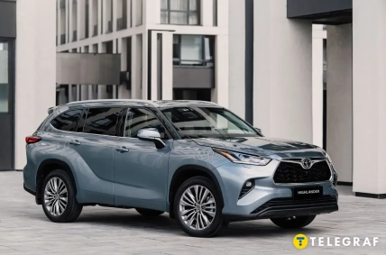 Серый Toyota Highlander стоит возле современного здания