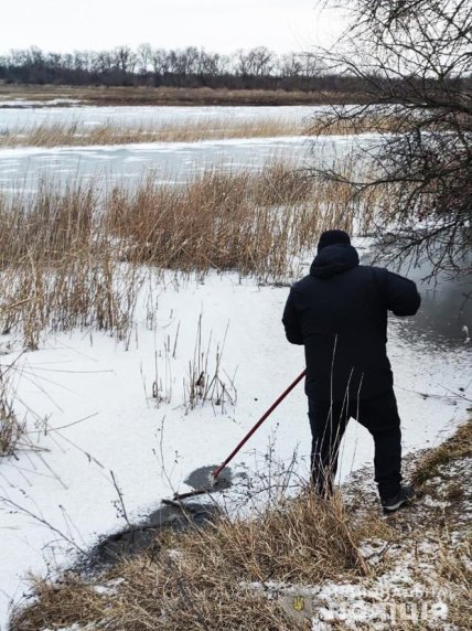Мужчина с багром у зимней реки
