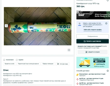 Длинный цилиндрический калейдоскоп с разноцветным геометрическим узором лежит на деревянном полу