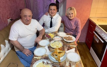 Двое мужчин и женщина сидят за столом с едой