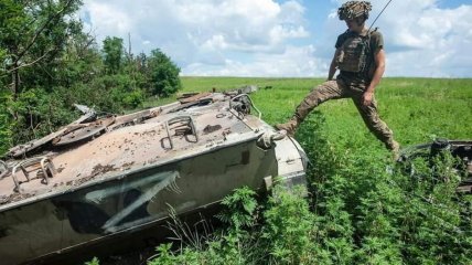 Боец ВСУ у подбитой российской боевой машины