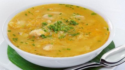 Аппетитная тарелка горохового супа с мясом, зеленью и гренками.