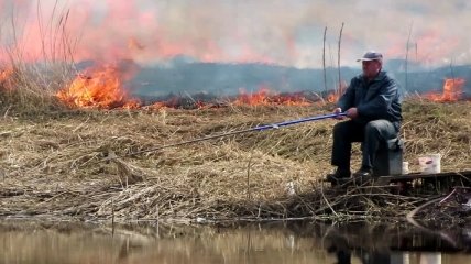 Нехай весь світ зачекає: чоловік не зупинив риболовлю незважаючи на пожежу (відео)