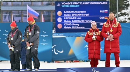 Линн Казмайер вместе со своим гидом Флорианом Бауманом отвернулись в сторону во время гимна России