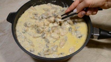 Курка з грибами та сиром у сметанному соусі на сковороді.