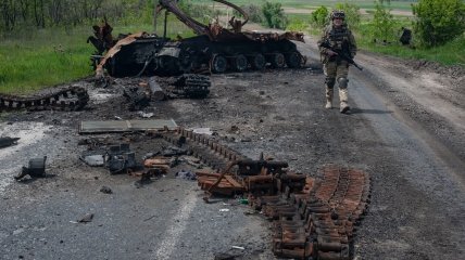 Украинский военный на фоне уничтоженного российского танка
