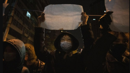 Протестующий держит чистый лист во время марша в Пекине. Воскресенье, 27 ноября 2022 г.