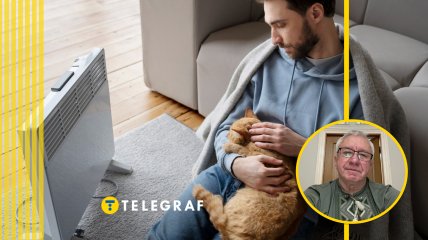 Мужчина с кошкой греется у обогревателя